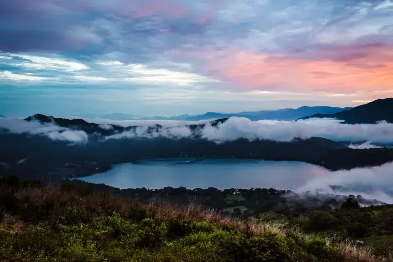 Majestic sunset over Santa María del Oro Lake with colorful clouds and lush greenery.