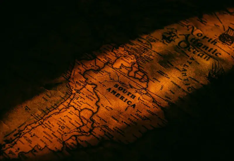 Close-up vintage map of South America illuminated by warm, artistic lighting giving a historical feel.