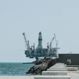 Distant view of an offshore oil rig with cranes on a sunny day.