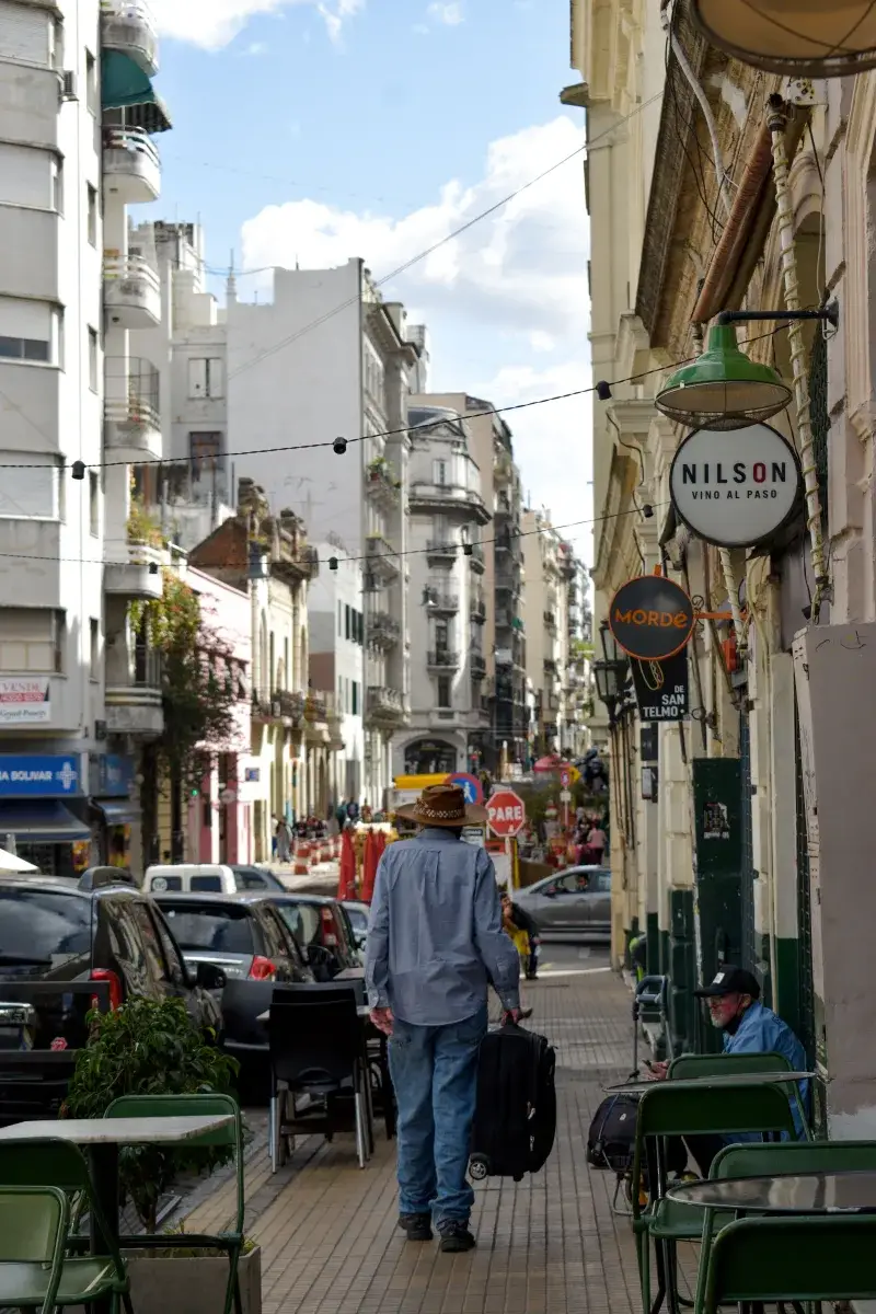 Tourist walking along a vibrant street in Buenos Aires, capturing urban life against classic architecture.