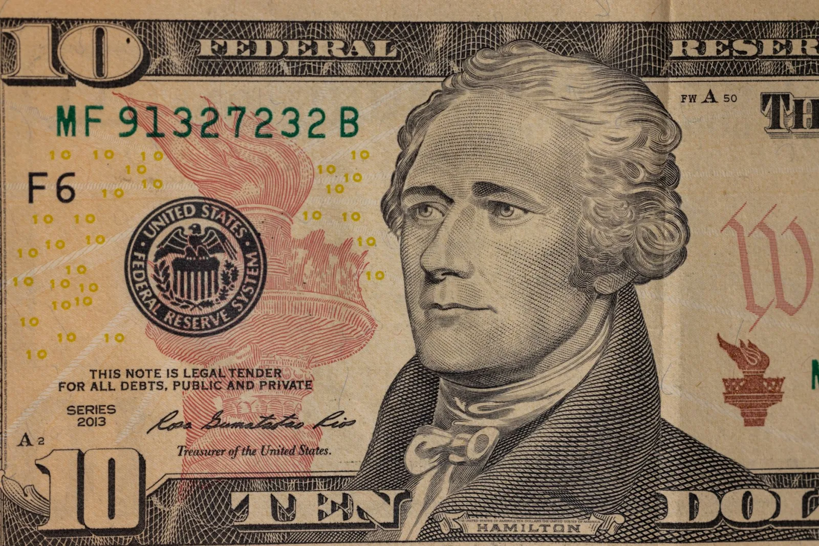 Detailed close-up image of a US ten dollar bill with Alexander Hamilton's portrait.