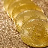 Close-up of golden Bitcoin coins on a shimmering glitter background, symbolizing digital currency's allure.